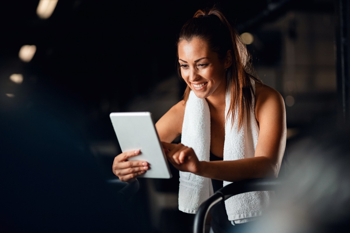 Woman planning workout on tablet at gym